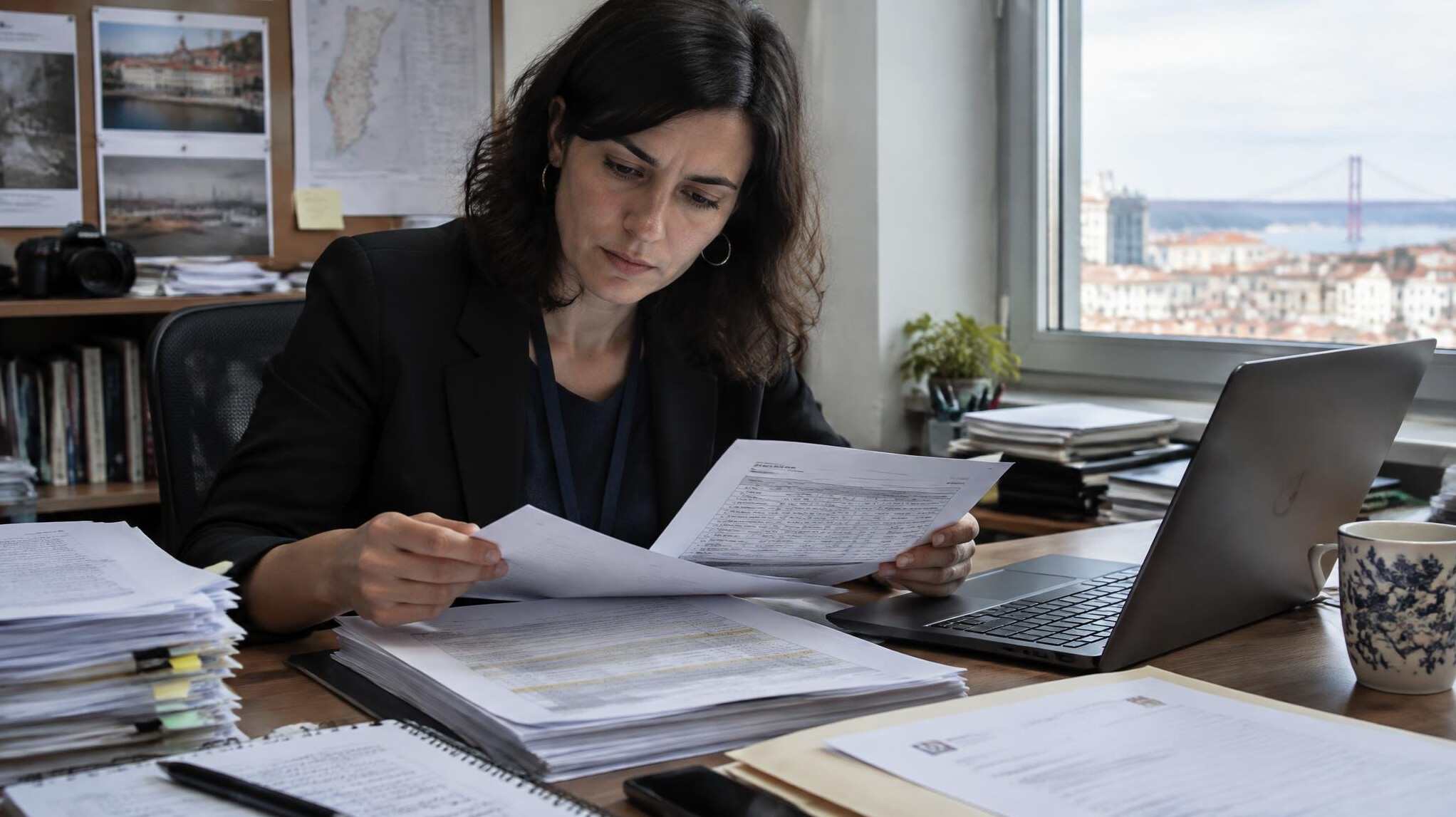Journalist reviewing printed documents and public contract records at a desk